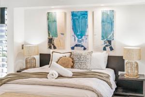 a bedroom with a large bed with blue paintings on the wall at Alex Beach House in Alexandra Headland