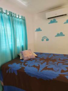 1 dormitorio con 1 cama con cortina azul en Fare Cocoon, en Punaauia
