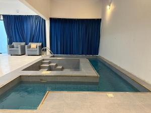 a swimming pool in a room with blue curtains at مزون السحاب in Al Maghrafīyah