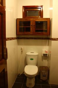 a bathroom with a toilet with a wooden cabinet above it at Timeless Apartment in Nha Trang