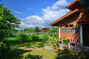 a garden with a brick building and a yard with plants at อยู่ดินกินดีฟาร์มสเตย์ in Mae Rim
