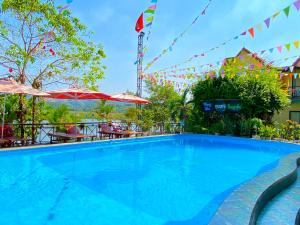 einen Pool in einem Resort mit Tischen und Sonnenschirmen in der Unterkunft Phong Nha Escape Bungalow in Phong Nha