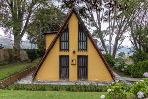 une petite maison jaune avec un toit triangulaire dans l'établissement Chalet Lander Colonia Tovar, à El Tigre