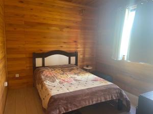 1 dormitorio con 1 cama en una pared de madera en CABANA DOCE LUAR, en Gravataí