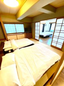 een slaapkamer met 2 bedden in een kamer met ramen bij La Foret Fujimi in Hiroshima