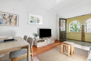 a living room with a television and a table and chairs at Acland Art Deco - Coastal Chic by St Kilda Beach in Melbourne