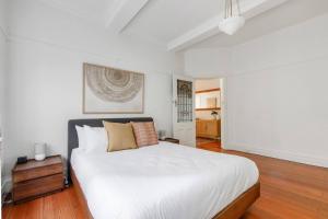 a bedroom with a large white bed and wooden floors at Acland Art Deco - Coastal Chic by St Kilda Beach in Melbourne