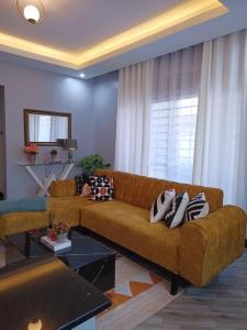 a living room with a brown couch and a window at Serene Homes 04 in Kampala