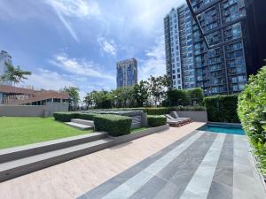 市中心URBITIA 精品公寓 في Klong Toi: حديقة بها مسبح وبعض المباني