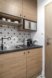a kitchen with a sink and wooden cabinets at Apartamenty Solo na Molo in Sopot