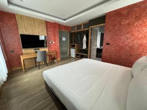 - une chambre avec un lit, un bureau et une télévision dans l'établissement La Isla Pranburi Beach Resort, à Sam Roi Yot