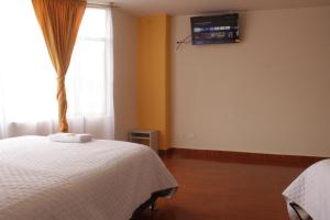 ein Schlafzimmer mit einem Bett und einem TV an der Wand in der Unterkunft Gran Hotel in Ipiales