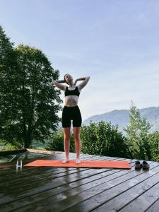 a woman standing on a yoga mat on a deck at Mirest - котедж в горах із чаном-джакузі in Slavske