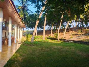a porch of a house with a lawn and trees at Luxury Beach Apartment in Hambantota