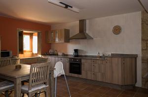 une cuisine avec des placards en bois et une table ainsi qu'une salle à manger dans l'établissement Casa Do Ghabino, à Santa Comba