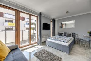 1 dormitorio con cama, sofá y ventana en STEGNA PARK B Apartamenty PIAMOLA en Stegna