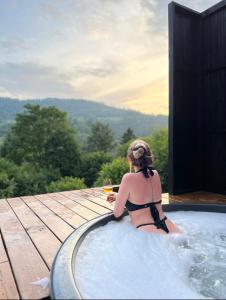 a woman in a bathing suit sitting in a hot tub at Mirest - котедж в горах із чаном-джакузі in Slavske