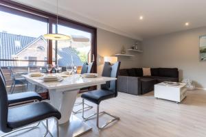 a dining room and living room with a table and chairs at Summer Diek Summerdiek 5 in Sankt Peter-Ording +9 photos