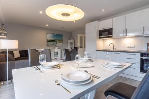 a kitchen and living room with a table with plates and wine glasses at Summer Diek Summerdiek 5 in Sankt Peter-Ording