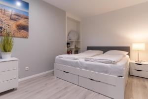 a white bedroom with a large bed and a desk at Summer Diek Summerdiek 5 in Sankt Peter-Ording