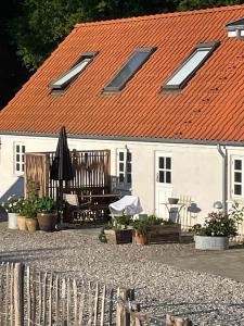 Casa blanca con techo naranja y patio en The Farm Guest House, en Svebølle