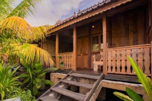a wooden house with a porch and a wooden bench at Pondok Cap Oleng Guesthouse Canggu by Ecommerceloka in Canggu