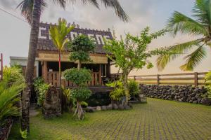 a house with a garden with palm trees in front of it at Pondok Cap Oleng Guesthouse Canggu by Ecommerceloka in Canggu