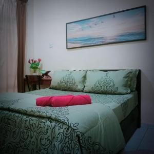 a bed with two pillows and a picture on the wall at HOMESTAY Duranta Home's in Batu Pahat