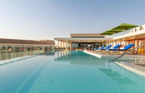 a swimming pool with blue chairs and a building at Aloft Al Ain in Al Ain