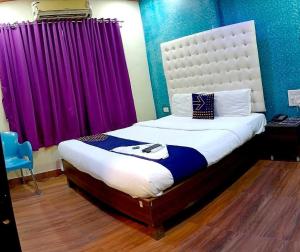 a bedroom with a large bed with purple curtains at OYO Flagship The Om Sai Residency in Mumbai