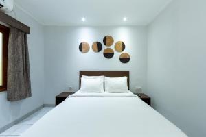 a bedroom with a white bed and two logs on the wall at Cove Matahari Guesthouse Sunset in Legian