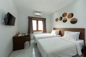 a hotel room with two beds and a television at Cove Matahari Guesthouse Sunset in Legian