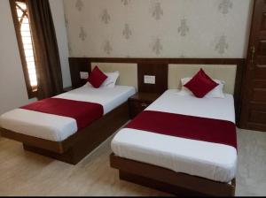 um quarto com 2 camas com lençóis vermelhos e brancos em Shoolin Palace em Mangalore