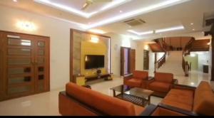 una sala de estar con sofás y TV en una habitación en Shoolin Palace, en Mangalore
