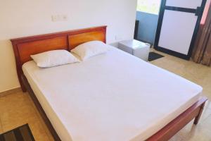 1 dormitorio con 1 cama blanca grande y cabecero de madera en Polhena Grand Resort & Banquet en Matara