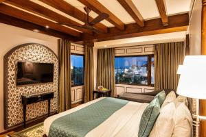 1 dormitorio con 1 cama, TV y ventanas en The Vintage Srinagar at Dal Lake en Srinagar