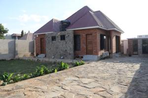a brick house with a stone driveway in front of it at Verified Lodge in Dodoma
