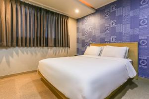 済州市にあるAliba Hotelの紫の壁のベッドルーム1室(大きな白いベッド1台付)