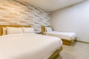 a bedroom with two beds and a stone wall at Aliba Hotel in Jeju