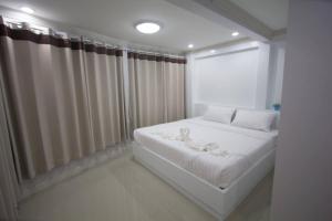 a bedroom with a white bed and a window at TG Home Residence in Chiang Rai