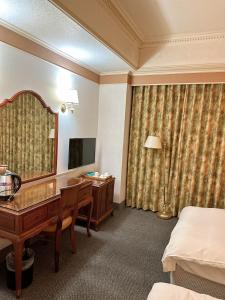 una camera d'albergo con scrivania e specchio di Duke Business Hotel a Taoyuan