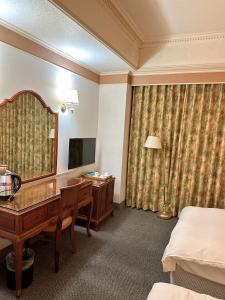 a hotel room with a desk and a mirror at Duke Business Hotel in Taoyuan