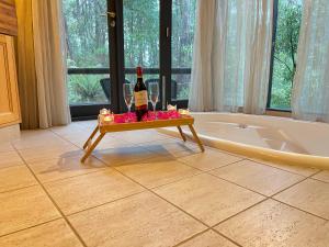 a bottle of wine on a tray next to a bath tub at Woodlands rainforest retreat in Narbethong