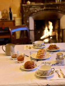 a table with plates of pastries and cups and a fireplace at Château de Belleaucourt 