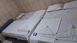 ein unmaskiertes Bett mit weißer Bettwäsche und einem lila Objekt darauf in der Unterkunft Espaço das Estrelas repousadas Suites in Praia do Forte
