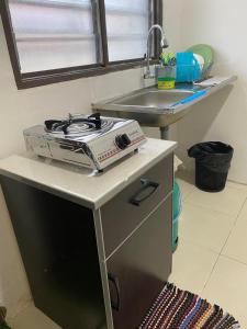 - une cuisine avec une cuisinière sur un comptoir à côté d'un évier dans l'établissement Cik Misi Homestay Jeniang, à Sik