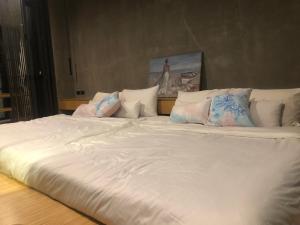 uma cama grande com lençóis brancos e almofadas em T House Cha-Am 