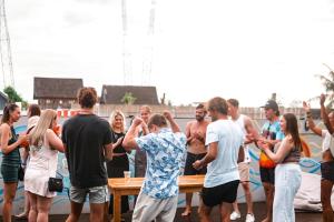 a group of people standing around a table on a boat at Surf & Party - Hostel Somewhere Else in Canggu