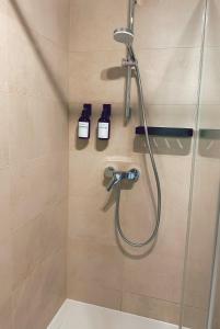 ein Badezimmer mit einer Dusche mit zwei Flaschen an der Wand in der Unterkunft Suites in Mödling in Mödling