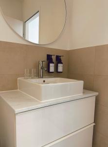 ein Badezimmer mit einem weißen Waschbecken und einem Spiegel in der Unterkunft Suites in Mödling in Mödling